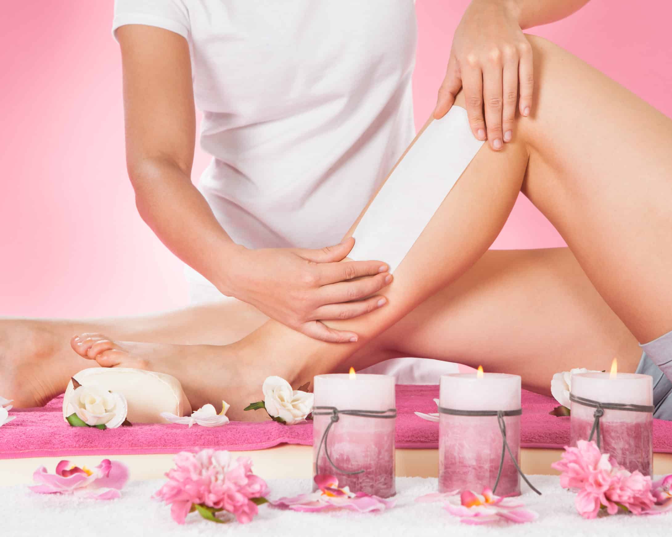 Midsection of female therapist waxing customer's leg at beauty spa